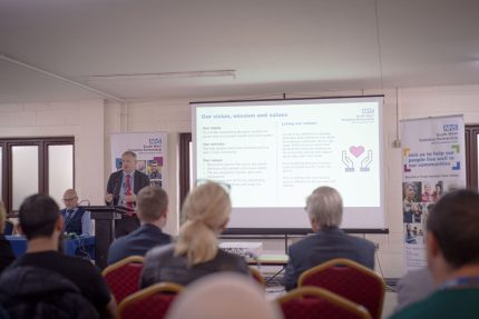 Phpto of person giving a presentation to a room of people
