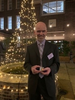 A man holding an award in front of a Christmas tree