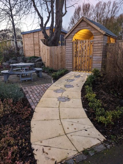 Photo of wooden lodge with paw print paving stones