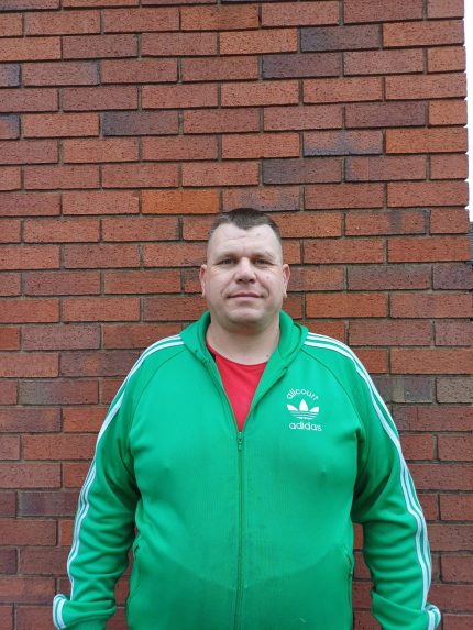 A photo of a man in a green top looking to camera