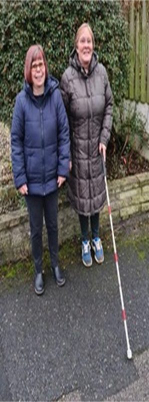 Two women standing together, one with a cane