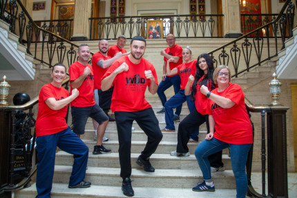 A group of men and women standing on a staircase. All wearing red tee-shirts that say World Homeless Day on.