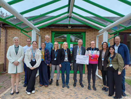 Colleagues standing outside the Cullingworth Street Hub with a sign to open the new sensory room