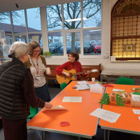 Person with guitar sat and two people standing talking