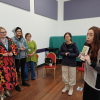 Recovery College Hong Kong delegation visit - person explaining the book in hand to others standing