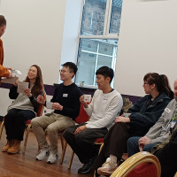 Recovery College Hong Kong delegation visit - person handing over object to another sitting down