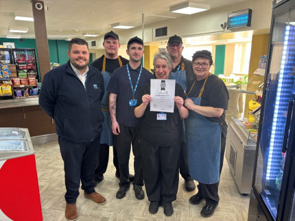 A group of people standing in a restaurant holding a certificate