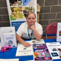 Colleague sat at a stall sharing leaflets and posters