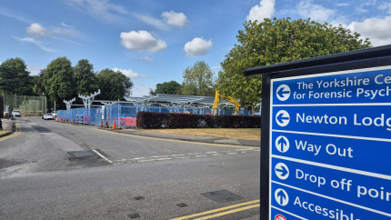 an image of a construction site building a solar car port frame with a sign for directions to Newton lodge