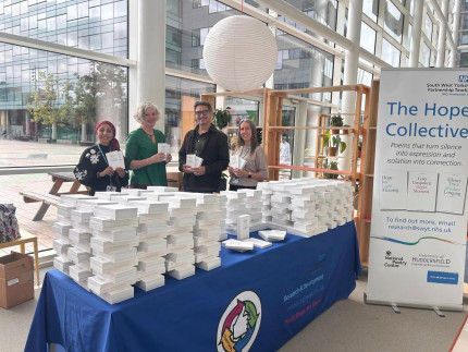 Photo of four people stood at an event table